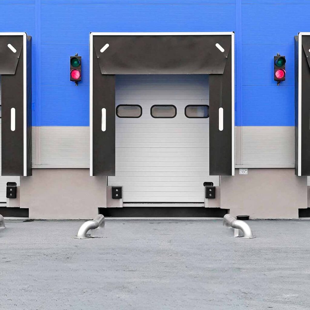 Porte sectionnelle industrielle FERMCO avec hublots, sas d'étanchéité, niveleur de quai et guides roues.
