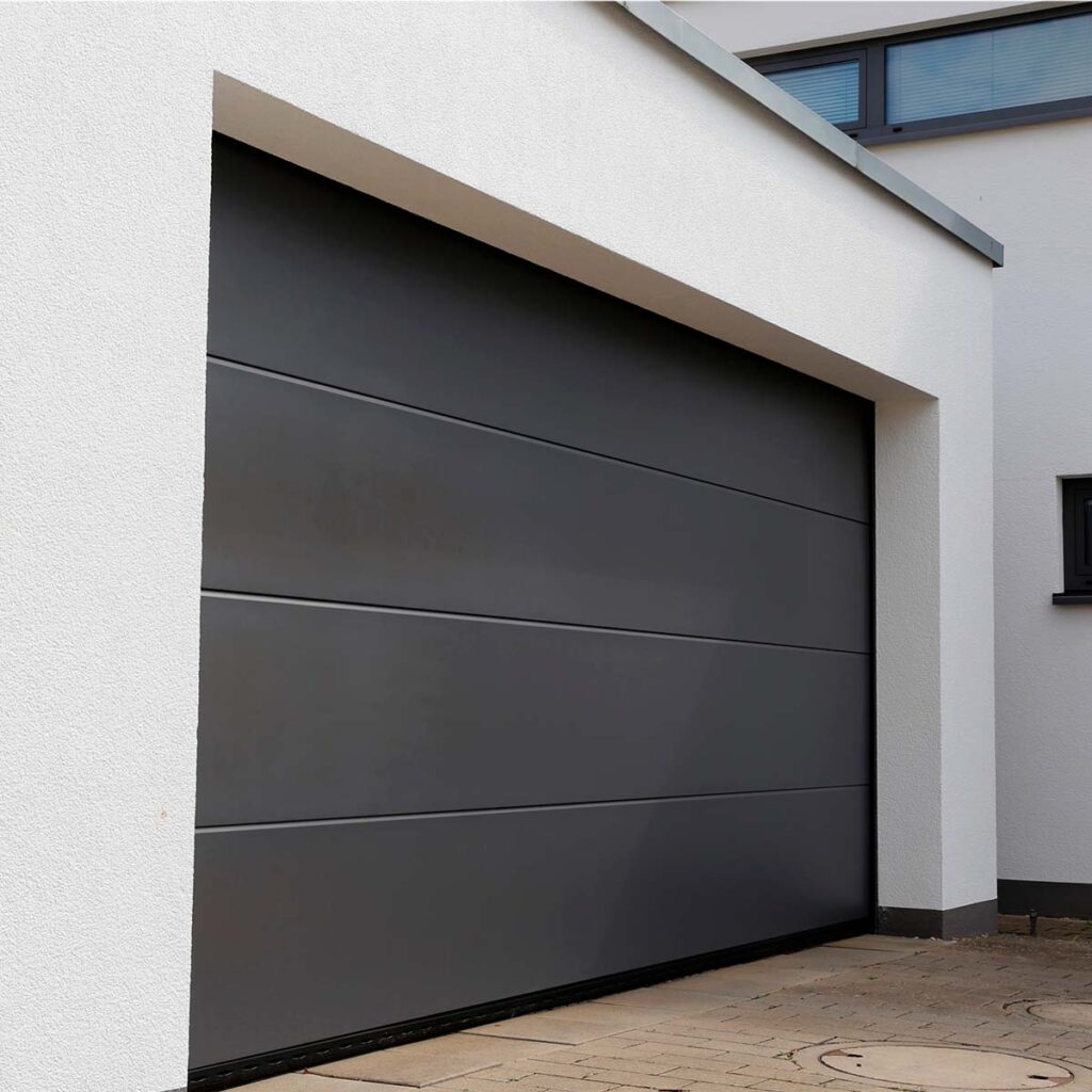 Porte de garage sectionnelle FERMCO en finition Sandgrain RAL 7016 en façade d'une villa contemporaine. Réunion.
