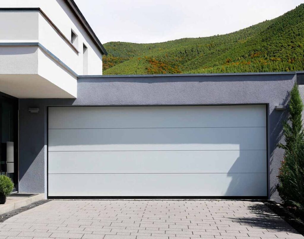 Porte de garage sectionnelle lisse blanche RAL 9010 en harmonie avec l'architecture contemporaine de la villa à la Réunion.